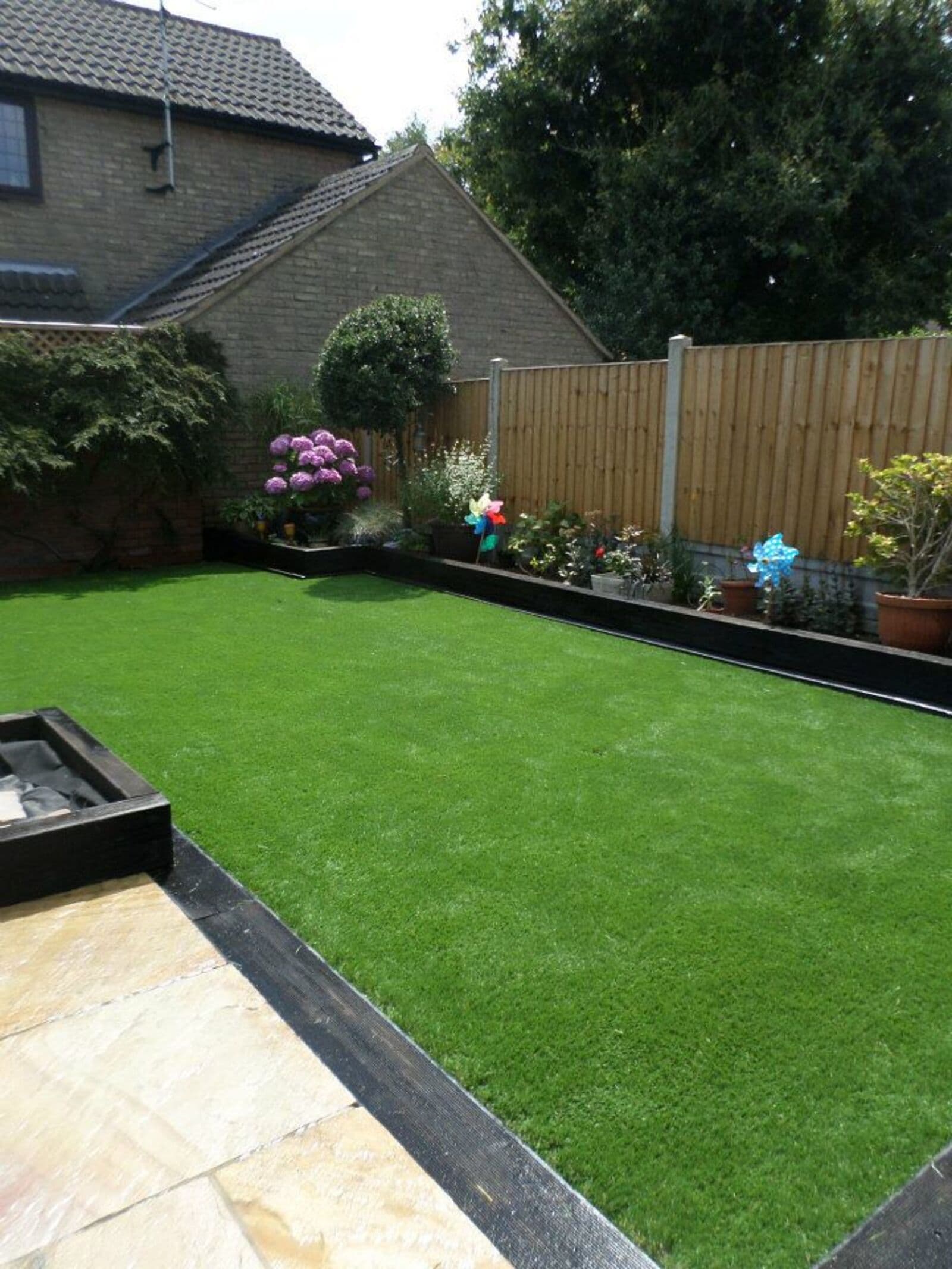 A uniform green lawn edged with paving slabs in an enclosed garden