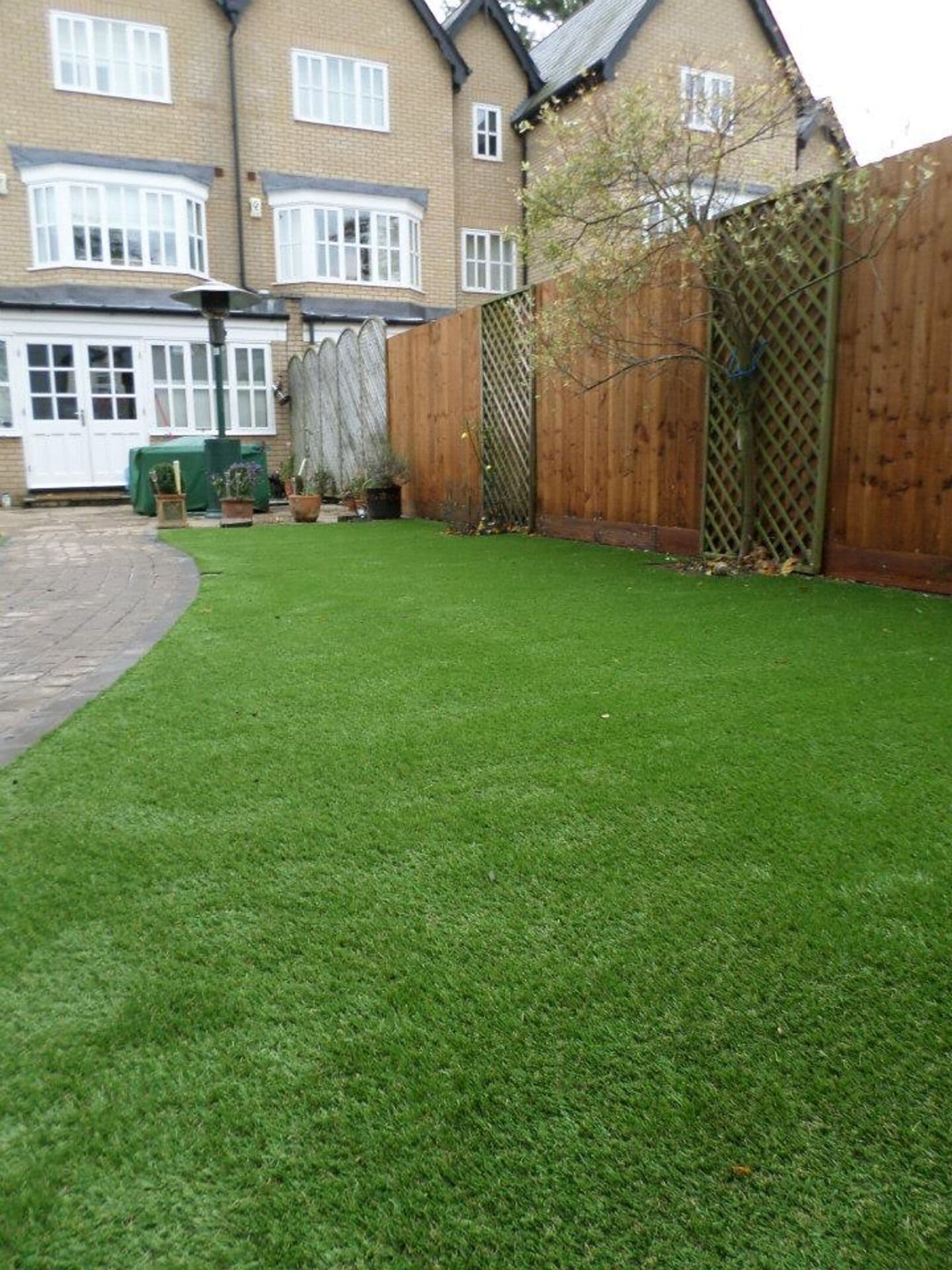 A neatly mown rectangular lawn running alongside a house and brick garden wall